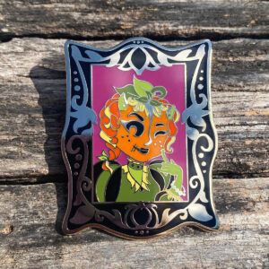 Pumpkin cutie Gothic Lady in a black Victorian frame enamel pin on a distressed wood background.