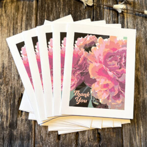 Thank You note cards with a close up of pastel peony flowers, and white envelopes, on a distressed wood background.