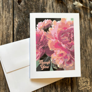 Thank You note card with a close up of pastel peony flowers, and white envelope, on a distressed wood background.